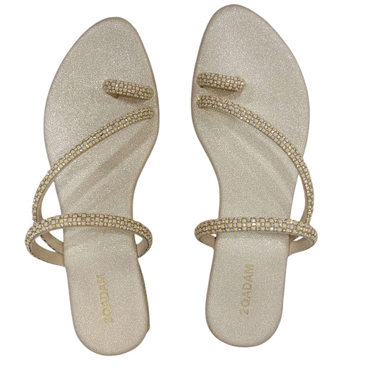 Pair of gold sandals with embellishments on a white background
